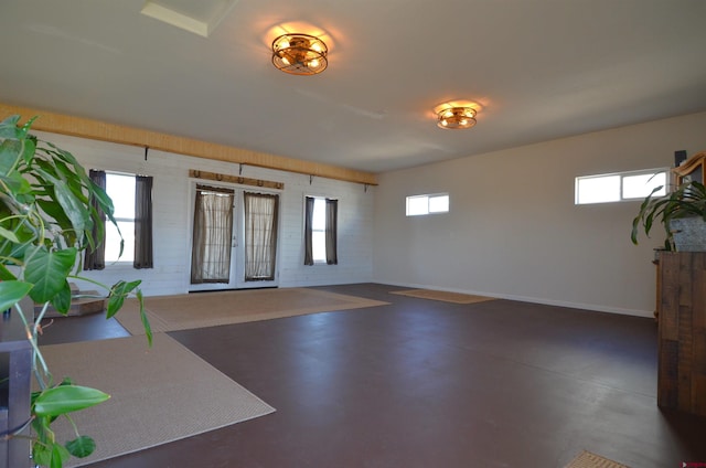 foyer with brick wall, baseboards, finished concrete flooring, and a healthy amount of sunlight