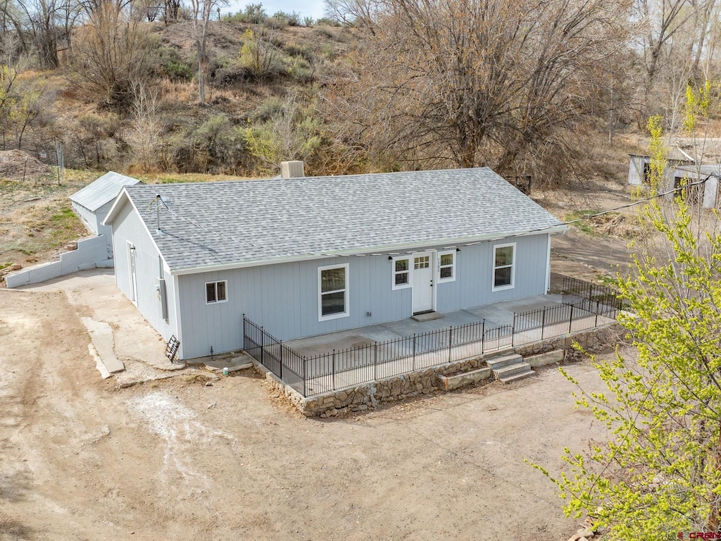 back of property with roof with shingles and fence