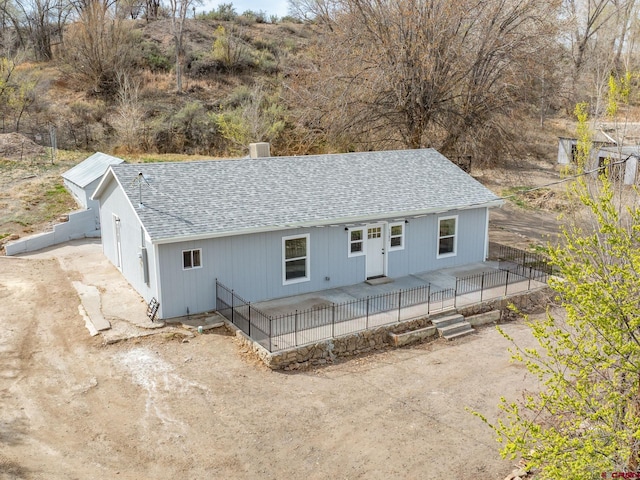 back of property with roof with shingles and fence