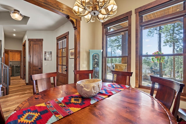 dining area with a chandelier, arched walkways, a wealth of natural light, and wood finished floors
