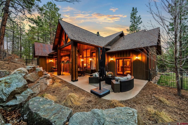 back of property featuring board and batten siding, fence, a patio, an outdoor hangout area, and roof with shingles