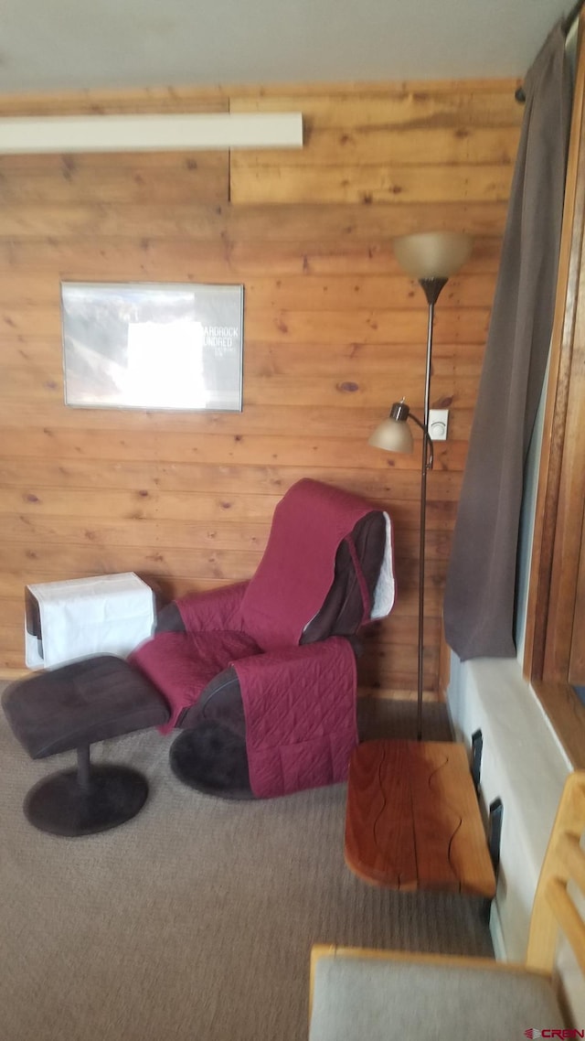 sitting room featuring wood walls and carpet flooring
