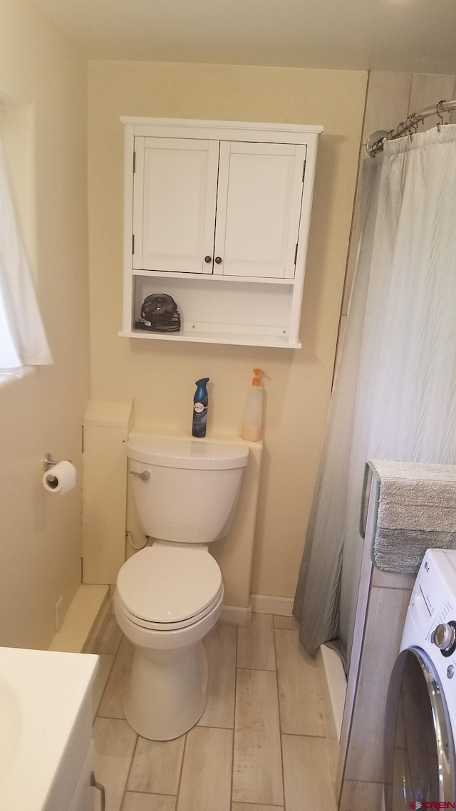 bathroom featuring washer / clothes dryer, baseboards, curtained shower, toilet, and tile patterned floors