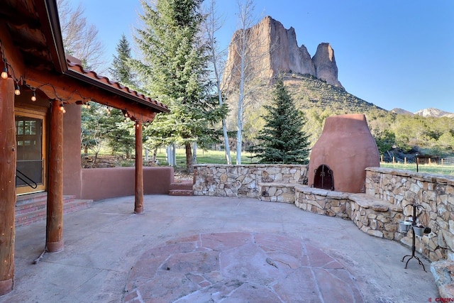 view of patio featuring a mountain view and exterior fireplace