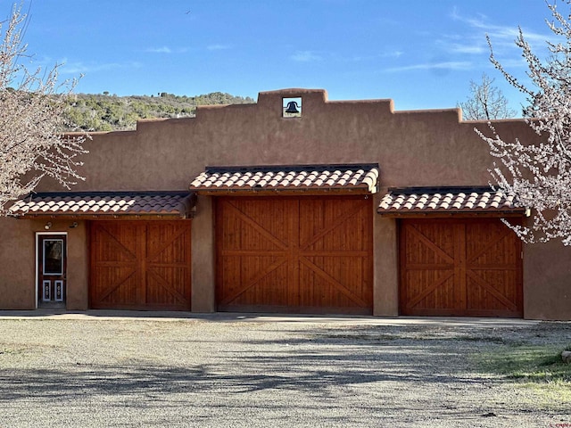 view of front of home featuring driveway, stucco siding, a tile roof, and a garage
