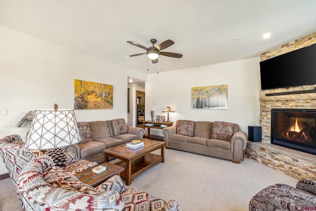 living area featuring a fireplace, a ceiling fan, and carpet floors