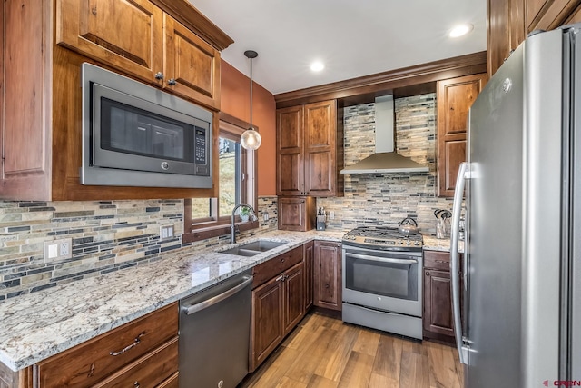 kitchen featuring wall chimney exhaust hood, light wood-style flooring, a sink, stainless steel appliances, and backsplash