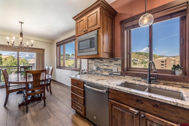 kitchen with a notable chandelier, a sink, dark wood-style flooring, stainless steel appliances, and backsplash