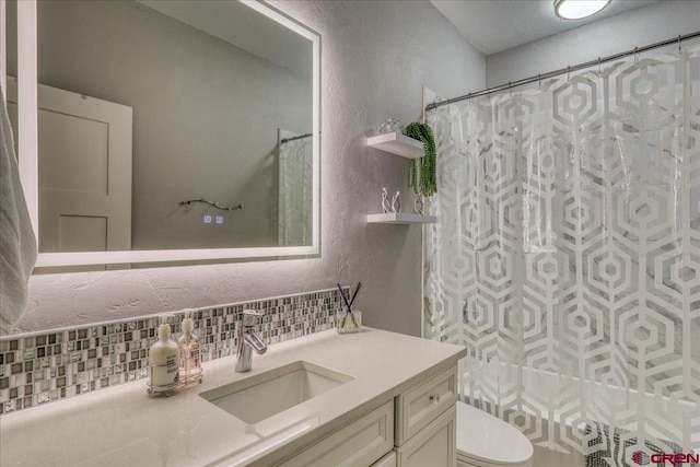 80 Cleek Ct, Pagosa Springs, CO 81147 - bathroom featuring curtained shower, toilet, a textured wall, vanity, and backsplash