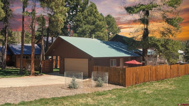 85 Dayspring Pl, Pagosa Springs, CO 81147 - property exterior at dusk featuring concrete driveway, metal roof, a garage, and a fenced front yard