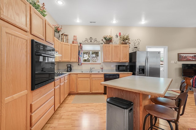 85 Dayspring Pl, Pagosa Springs, CO 81147 - kitchen with light brown cabinets, light wood-style flooring, black appliances, a kitchen bar, and a sink