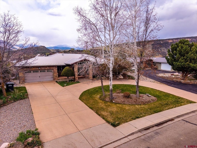 ranch-style house with an attached garage, driveway, a front yard, and a mountain view