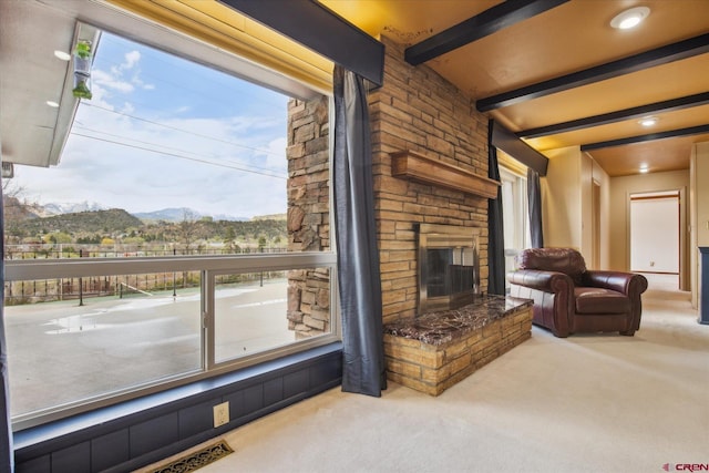 carpeted living area featuring a wealth of natural light, exterior fireplace, beam ceiling, and a mountain view