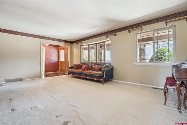 living room featuring baseboards, visible vents, carpet floors, and a healthy amount of sunlight