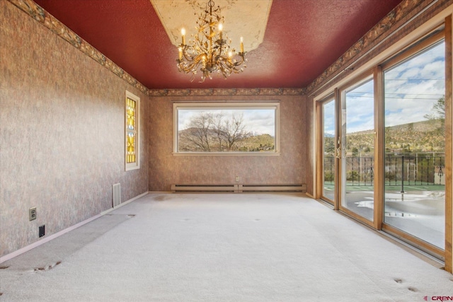 interior space with a baseboard heating unit, plenty of natural light, carpet flooring, and an inviting chandelier