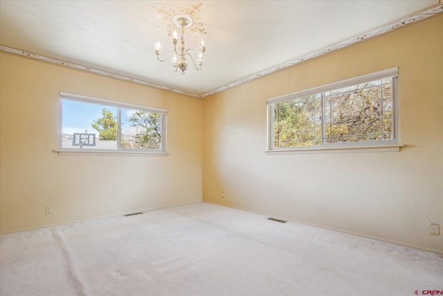 unfurnished room featuring carpet floors, a wealth of natural light, a notable chandelier, and visible vents