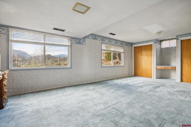 unfurnished bedroom with carpet floors, visible vents, and wallpapered walls