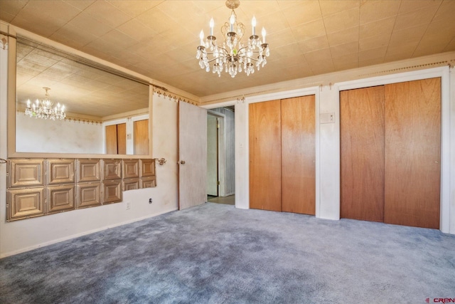 unfurnished bedroom featuring multiple closets, carpet floors, and a chandelier