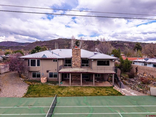 exterior space featuring a deck with mountain view, fence, stairs, a yard, and a patio