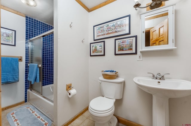 bathroom with baseboards, toilet, a sink, and combined bath / shower with glass door