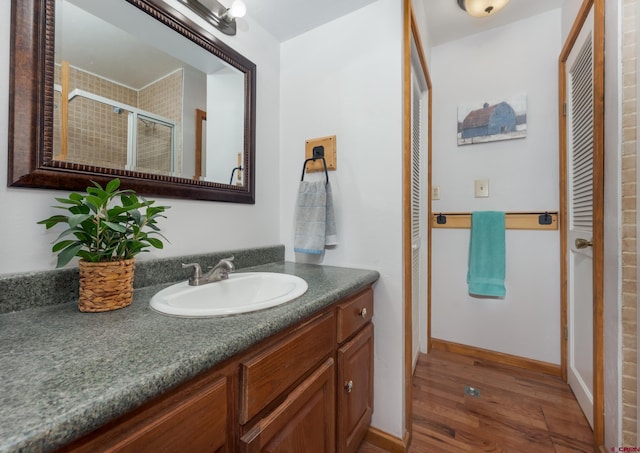 bathroom with wood finished floors, vanity, and a stall shower