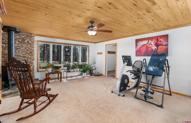 workout room featuring ceiling fan, wooden ceiling, carpet floors, and a wood stove