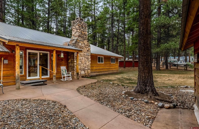 doorway to property featuring a chimney and metal roof
