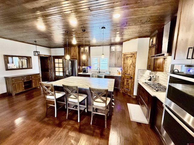 kitchen featuring dark wood finished floors, wooden ceiling, a center island, a kitchen bar, and appliances with stainless steel finishes