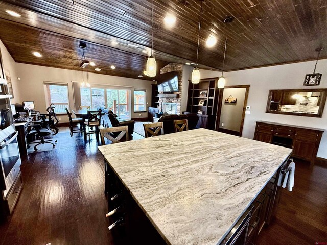 kitchen featuring stainless steel oven, wooden ceiling, a stone fireplace, and dark wood-type flooring