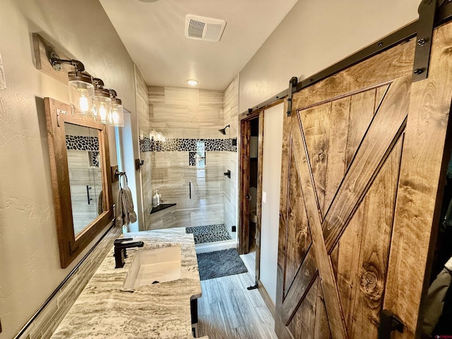full bath with wood finished floors, a stall shower, vanity, a textured wall, and visible vents