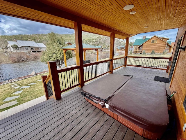 deck featuring a gazebo, a lawn, and a water view