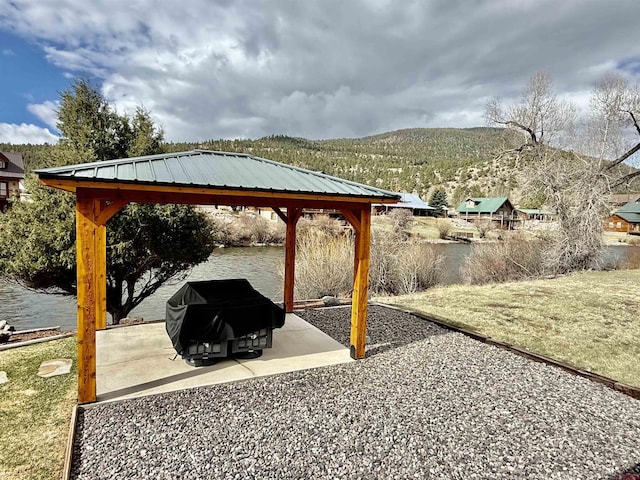 view of patio / terrace featuring a water and mountain view, a grill, and a gazebo