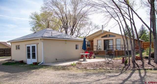 rear view of house featuring stucco siding, fence, and a patio area