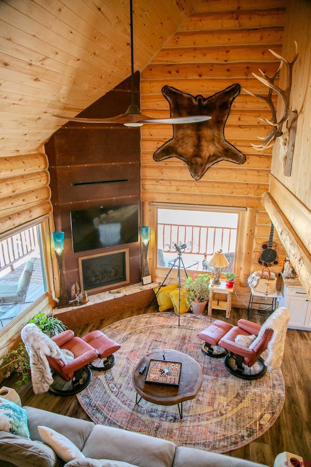 living area featuring rustic walls, wood finished floors, a fireplace, and wooden ceiling