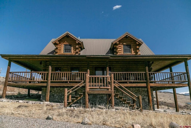 view of front of home with stairs, log exterior, and metal roof
