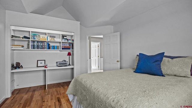 bedroom with vaulted ceiling and wood finished floors