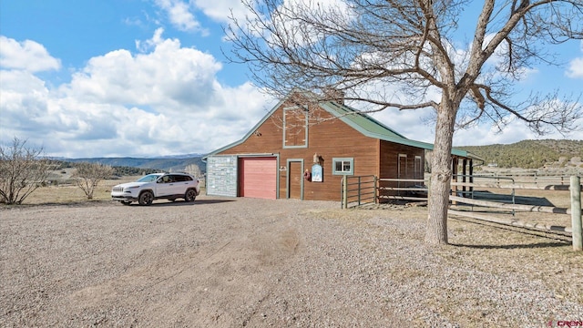 view of barn featuring driveway, a mountain view, and an exterior structure