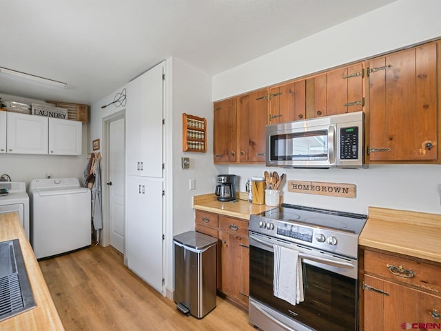 kitchen with brown cabinets, light countertops, washing machine and dryer, light wood-type flooring, and appliances with stainless steel finishes