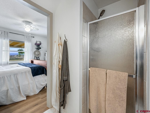 ensuite bathroom with wood finished floors, a ceiling fan, ensuite bath, and a shower stall
