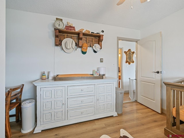 bedroom with ceiling fan, a textured ceiling, and light wood-style flooring