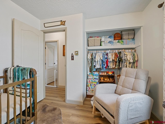 sitting room featuring an upstairs landing, baseboards, a textured ceiling, and light wood-type flooring