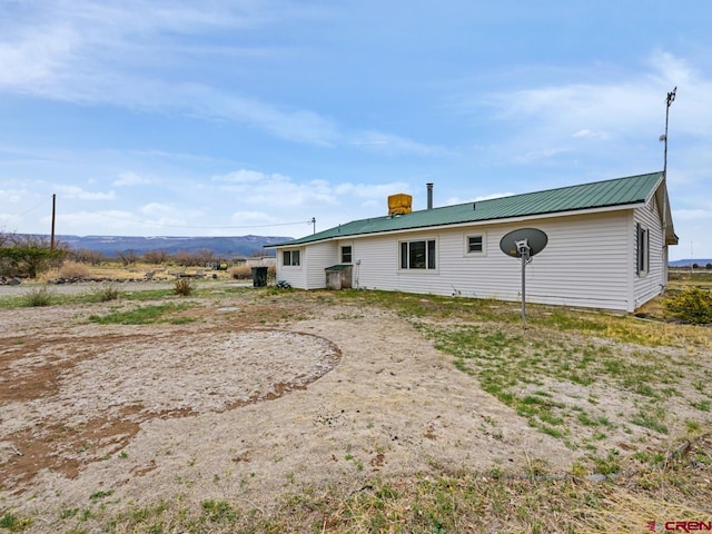 rear view of house featuring a chimney and metal roof