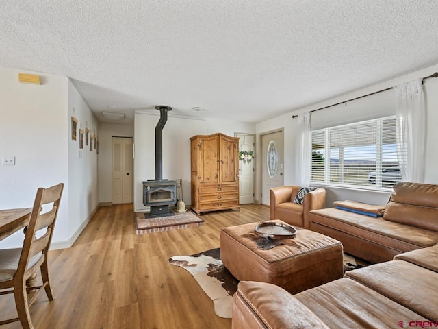 living room with a textured ceiling, light wood-style floors, and a wood stove