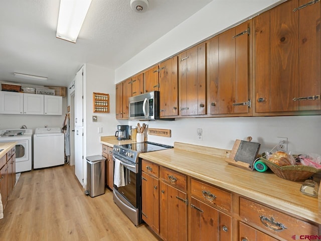 kitchen with stainless steel appliances, washer and clothes dryer, light countertops, light wood-type flooring, and brown cabinetry