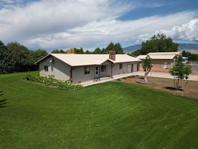 14894 Deer Run Rd, Delta, CO 81416 - back of property with a chimney, concrete driveway, a garage, and a yard