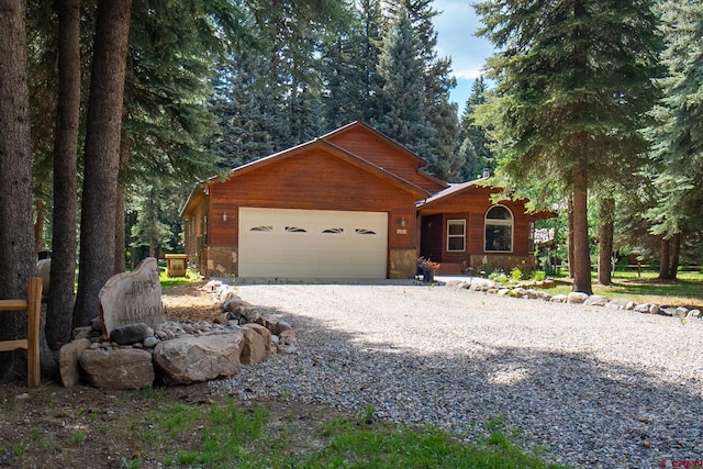 chalet / cabin featuring an attached garage and gravel driveway