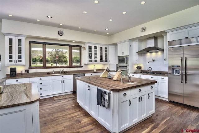 3575 E Rd, Palisade, CO 81526 - kitchen featuring wall chimney range hood, a sink, a center island with sink, wood counters, and built in appliances