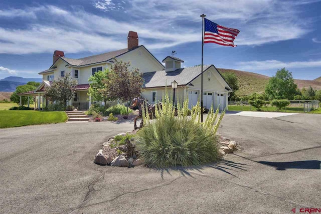 3575 E Rd, Palisade, CO 81526 - view of front of house with a garage, a chimney, aphalt driveway, and a mountain view