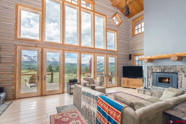 living area featuring french doors, a stone fireplace, hardwood / wood-style flooring, wooden ceiling, and high vaulted ceiling