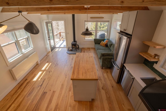 living area featuring a wealth of natural light, a wood stove, and light wood finished floors